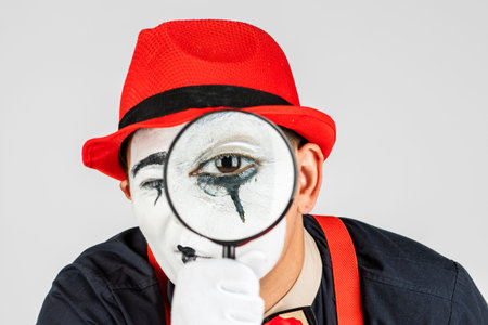 Male mime looking through the magnifying glass. isolated on white background