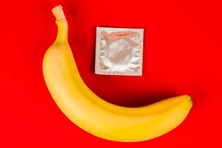 A condom and a banana, safe sex. Sex toy. On red backgroundの写真素材