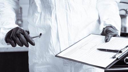 A policeman looks through a magnifying glass at the evidence at the crime scene. The crime scene of...