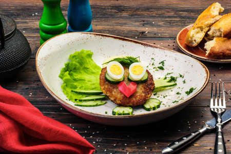 Juicy tasty meat fried cutlets with hot mashed potatoes, green lettuce leaves, on a white plate with cutleryの写真素材