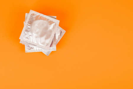Condoms on an orange background. The concept of prevention and safe sexの写真素材