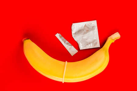 A condom and a banana, safe sex. Sex toy. On red backgroundの写真素材