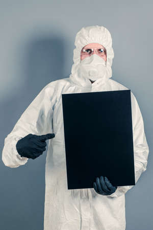 A medical scientist or policeman in protective clothing holds an empty banner for your advertisement. The concept of health and crimeの写真素材