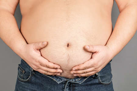 fat man, checking his weight, on a gray background.の写真素材