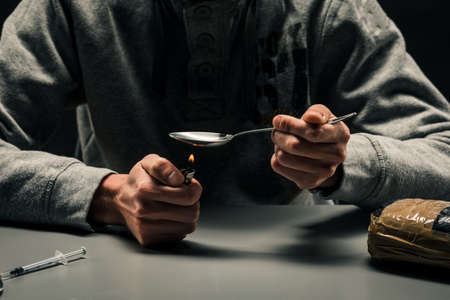 Close-up of a man preparing drugs with a lighter. The concept of addiction
