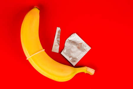 A condom and a banana, safe sex. Sex toy. On red backgroundの写真素材