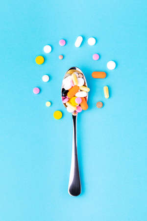 lots of tablets on spoon isolated on blue backgroundの写真素材