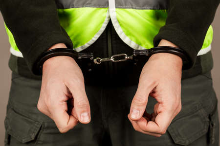 man in the yellow vest is handcuffedの写真素材