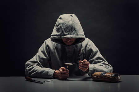 Close-up of a man preparing drugs with a lighter. The concept of addictionの写真素材