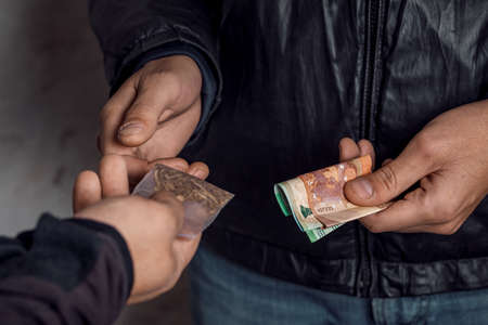 A person with money buys a dose of cocaine or heroin or other drug from a drug dealer.