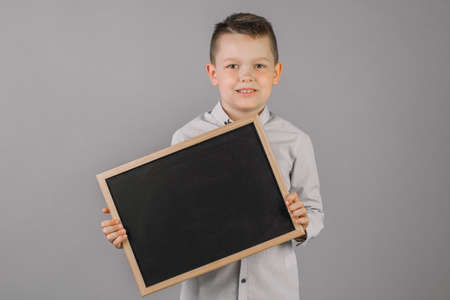 Portrait of a little boy holding a Board on a gray backgroundの写真素材