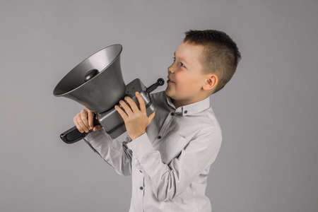 A boy with a Megaphone makes an announcement with a copy of the space on a gray background