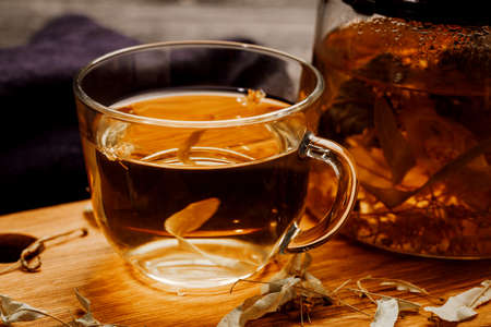 Glass cup of tea with linden on wooden table