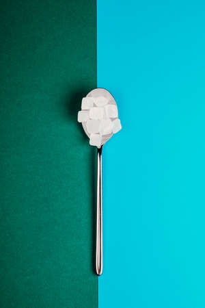 Sugar-replacing tablets with a spoon on a green and blue background.の写真素材