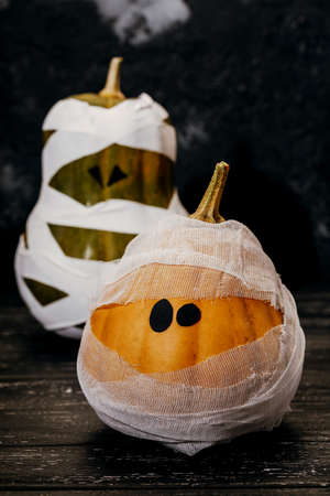 Zombie pumpkins in bandages, on a dark background. The concept of Halloween.の写真素材