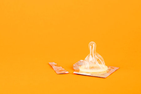 Condoms on an orange background. The concept of prevention and safe sexの写真素材