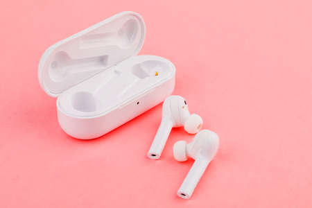 a pair of white headphones on pink background.