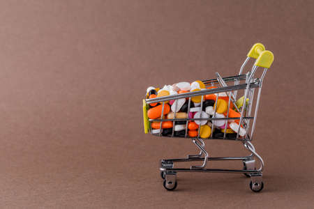 Pills and shopping cart on a yellow background Concept of buying drugs, prices for treatment. Sale in the pharmacyの写真素材