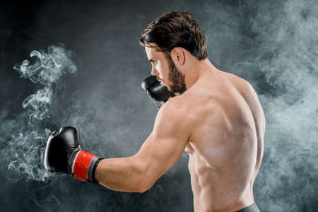 A man in Boxing gloves. A man Boxing on a black background. The concept of a healthy lifestyle.の写真素材