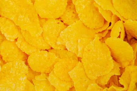 Corn flakes are scattered on the table as a background and texture.