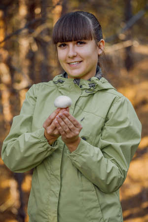 beatiful girl picking mushrooms in the autumn forest.の写真素材