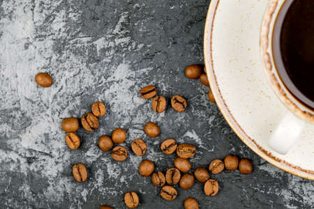 A Cup of coffee with roasted beans on a stone background. Top view with space for textの写真素材