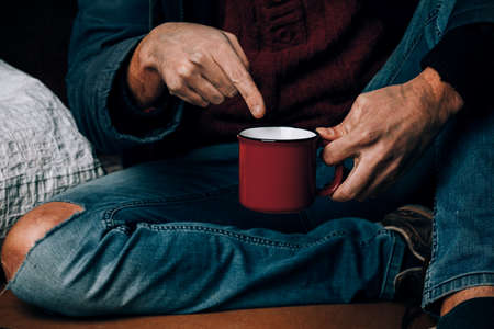 A man begs. He is holding a white paper Cup. The concept of homelessness and povertyの写真素材