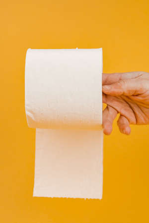 A roll of toilet paper in a woman's hand on a yellow background.の写真素材