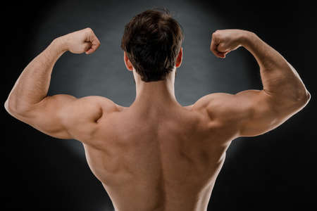The athletic man raised his outstretched arms, the athlete's muscular body visible from behind...