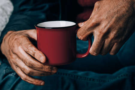 A man begs. He is holding a white paper Cup. The concept of homelessness and povertyの写真素材