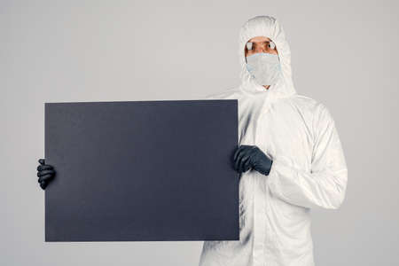 A man in a uniform and face mask holding a placard. Concept of healthcare and medicine.の写真素材