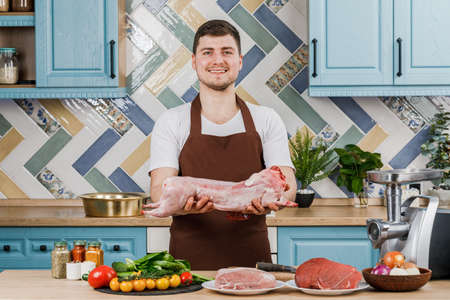 Young beautiful male chef presents food in the kitchenの写真素材