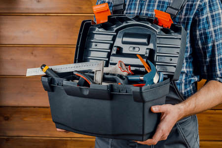 Construction and repair - a male worker or Builder with working tools in a box.の写真素材