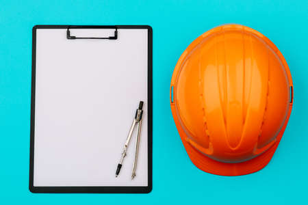 Top view with an orange safety engineer's helmet and an empty Notepad on a blue background.の写真素材