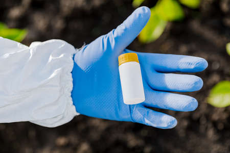 scientist's hand holds a jar of earth samples for analysisの写真素材
