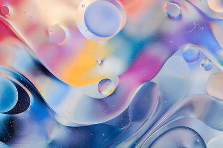 Close-up of the movement of oil droplets on the water surface. Colorful abstract macro background of...