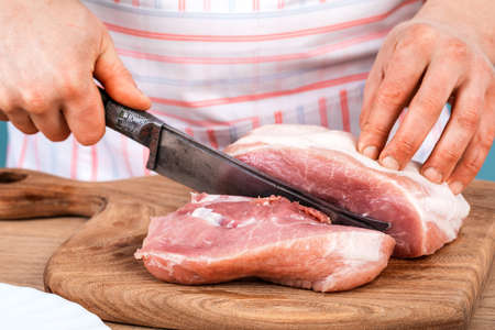 Cook cuts a piece of fresh meat, cuts meat in the kitchen.