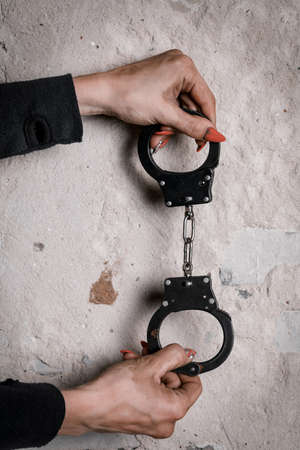 Close-up of hands in handcuffs, female prisoner, arrested woman in handcuffs. The concept of crime.の写真素材