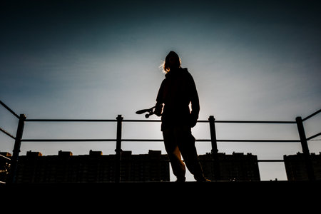 Silhouette of a male skateboarder doing a somersault trick in a skate Park.