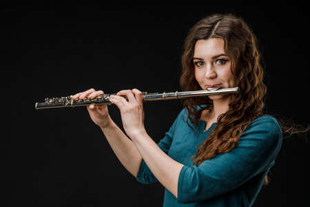 Portrait of a woman playing a transverse flute, isolated on a black backgroundの写真素材
