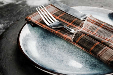 Black round slate board with cutlery on dark stone texture top view. Place for a menu or recipe.の写真素材