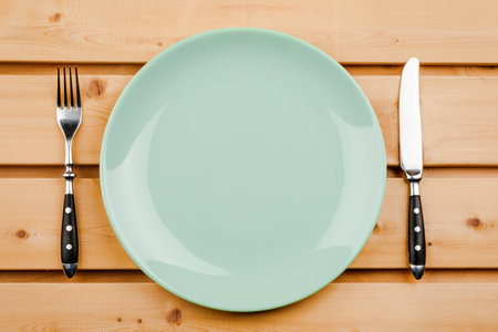 Empty plate with cutlery on a wooden tableの写真素材