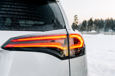 The headlights of a car. Close-up of the rear light of a car on a winter road.の写真素材