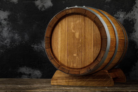 A beautiful wooden barrel and a worn oak wood table set against a dark wall pattern for the design.の写真素材