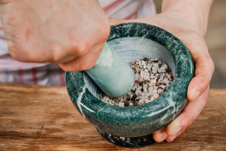 A male chef grinds spices and herbs in a cooking mortar.の写真素材