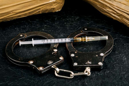 Heroin in a syringe on the dark cement floor. An addictive substance, a drug, an illegal thing, the concept of a dangerous drug.の写真素材