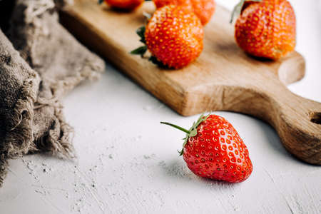 Fresh juicy strawberries with leaves on a white concrete background.の写真素材