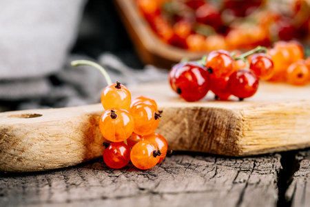 Ripe red currant berries in a bowl. Fresh red currants on a dark rustic wooden table. Background...