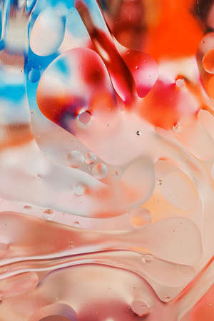 Close-up of the movement of oil droplets on the water surface. Colorful abstract macro background of oil drops on the water surfaceの写真素材