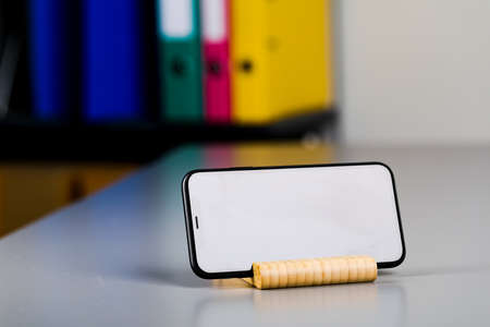 A black smartphone on a wooden stand is lying on the table. A place to copy.の写真素材